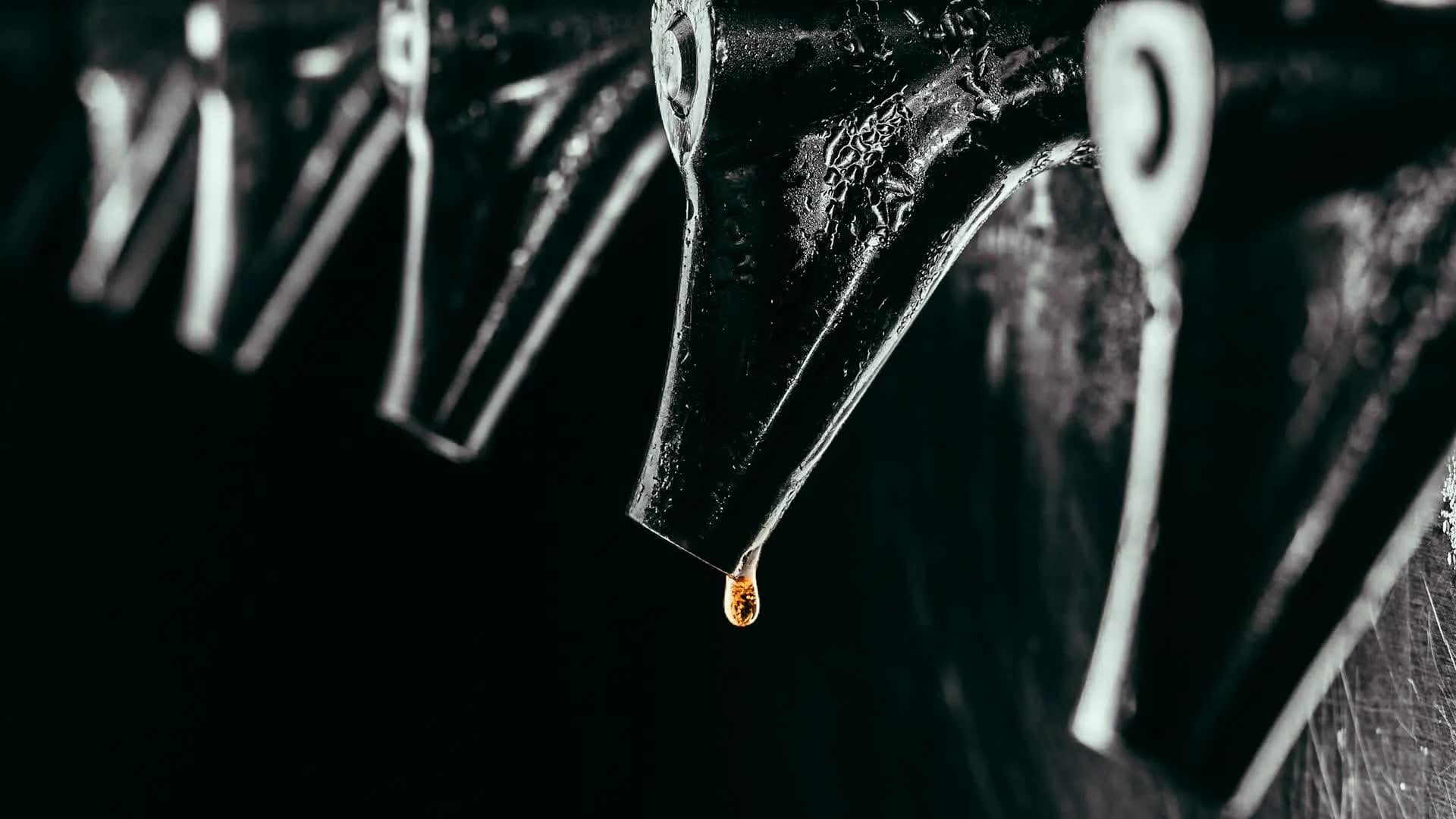 A single drop of amber beer falling from a tap